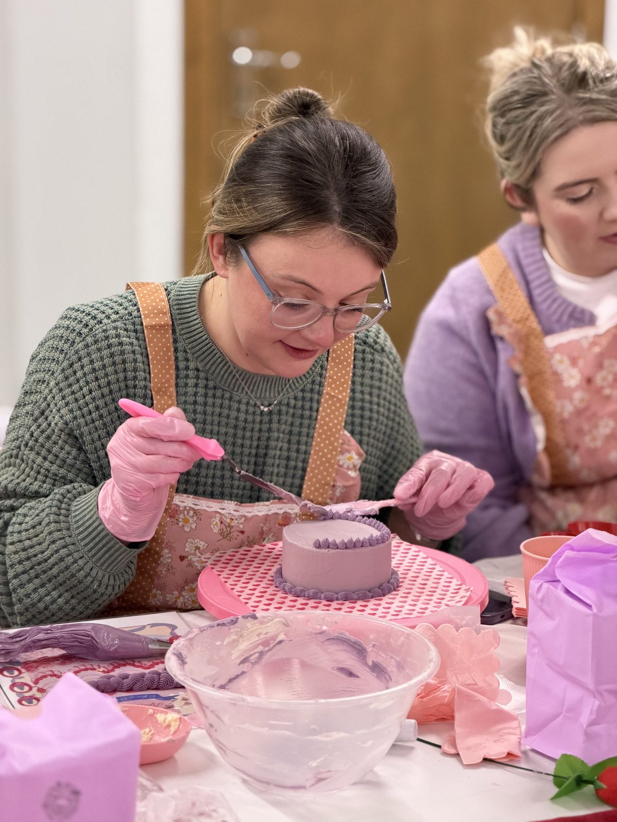 Close-up of attendee decorating a lilac cake
