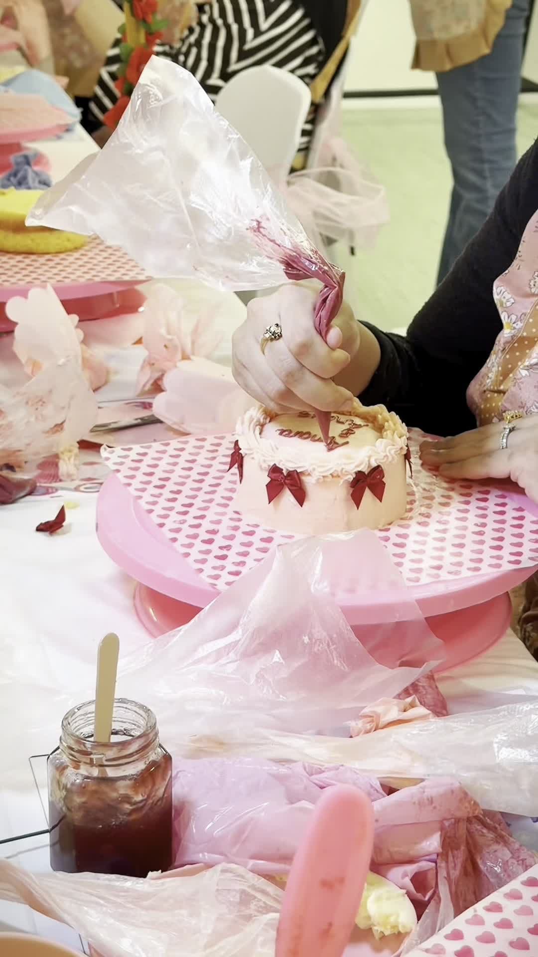 Close-up piping decorative bows onto a cake