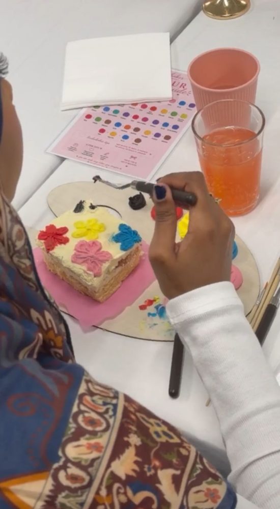 Painting buttercream flowers onto a square cake with a palette